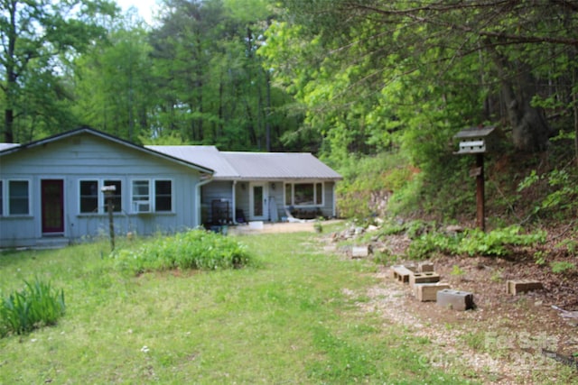 view of front of house featuring a front lawn, board and batten siding, and metal roof