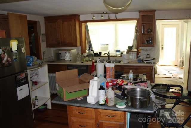 kitchen with brown cabinetry, a sink, freestanding refrigerator, radiator heating unit, and black dishwasher