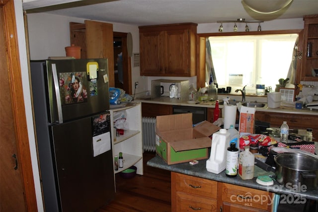 kitchen with brown cabinets, a sink, radiator, freestanding refrigerator, and dark wood-style floors