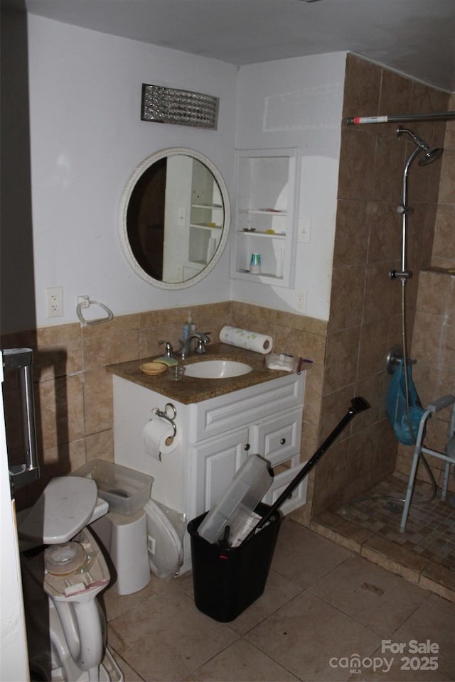bathroom with tile walls, a tile shower, and vanity