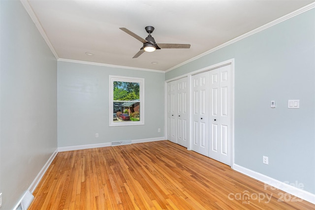6007 Charing Pl, Charlotte, NC 28211 - unfurnished bedroom with multiple closets, light wood-style flooring, crown molding, baseboards, and a ceiling fan