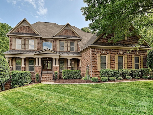 craftsman house featuring brick siding, a front lawn, covered porch, and a standing seam roof