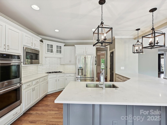 kitchen featuring light countertops, a sink, an inviting chandelier, ornamental molding, and stainless steel appliances