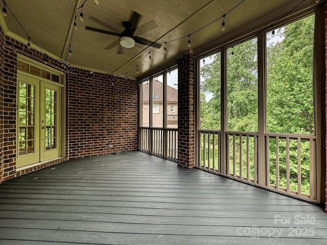 unfurnished sunroom featuring a ceiling fan and french doors