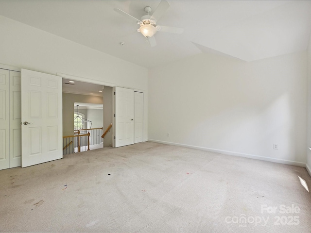 carpeted empty room with baseboards, a ceiling fan, and vaulted ceiling