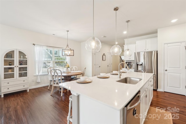 kitchen with a sink, light countertops, stainless steel appliances, and dark wood-style floors