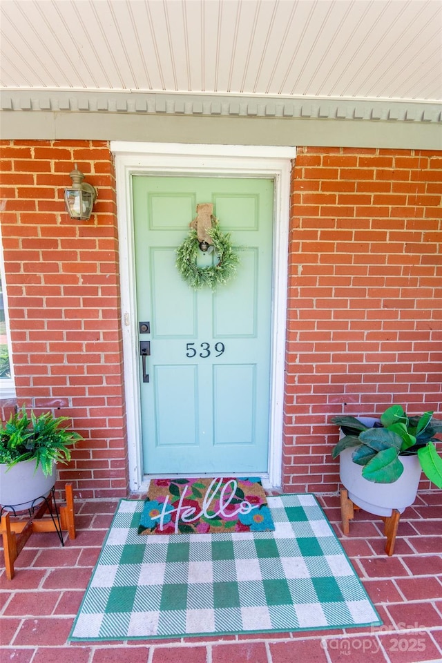 doorway to property featuring brick siding