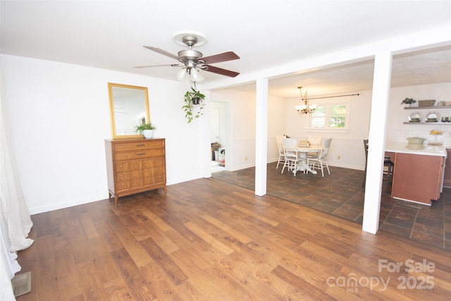 living area featuring ceiling fan with notable chandelier and dark wood-style floors