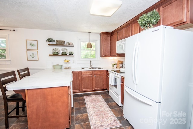 kitchen featuring white appliances, a peninsula, plenty of natural light, and a sink