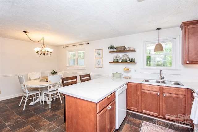 kitchen with white dishwasher, a textured ceiling, a sink, and a peninsula