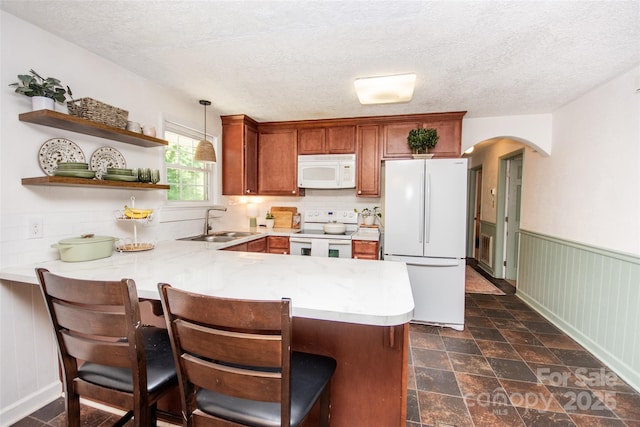 kitchen with white appliances, a peninsula, a sink, and light countertops