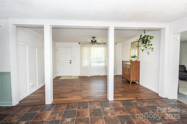 entryway featuring a textured ceiling, ceiling fan, stone finish flooring, and baseboards