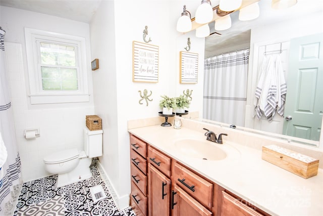 bathroom with vanity, tile patterned flooring, baseboards, and toilet