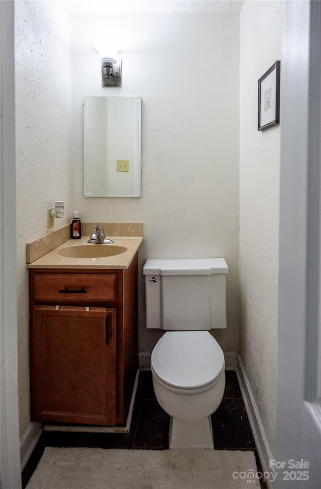 bathroom featuring vanity, baseboards, tile patterned floors, and toilet