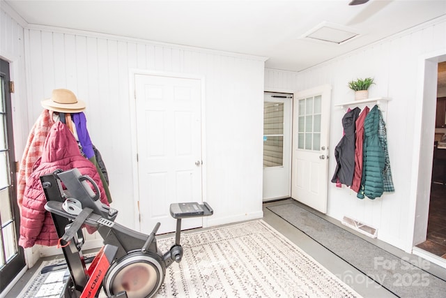 workout room featuring visible vents, attic access, and wood walls