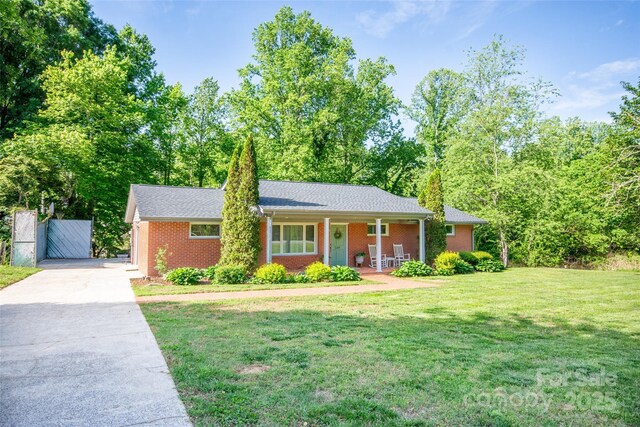 single story home with covered porch, brick siding, and a front lawn