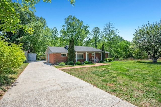 ranch-style house with fence, a front lawn, brick siding, a porch, and concrete driveway