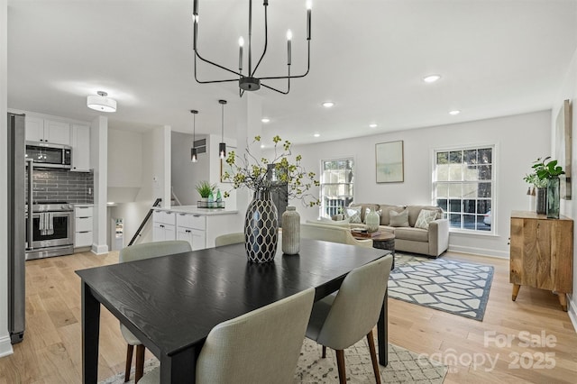 dining space featuring light wood-style floors, recessed lighting, and a chandelier