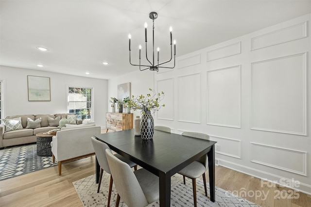 dining area featuring recessed lighting, light wood-style floors, an inviting chandelier, and a decorative wall