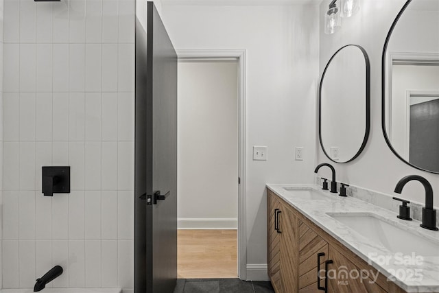 bathroom featuring a sink, baseboards, and double vanity