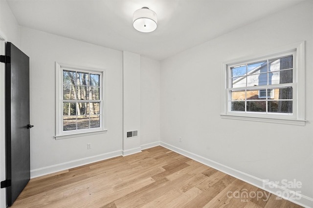 empty room with baseboards, light wood-style flooring, and plenty of natural light