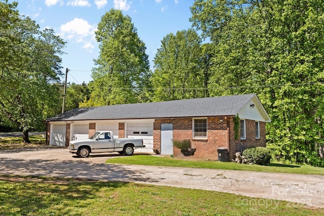 exterior space featuring brick siding, dirt driveway, a garage, and a front yard