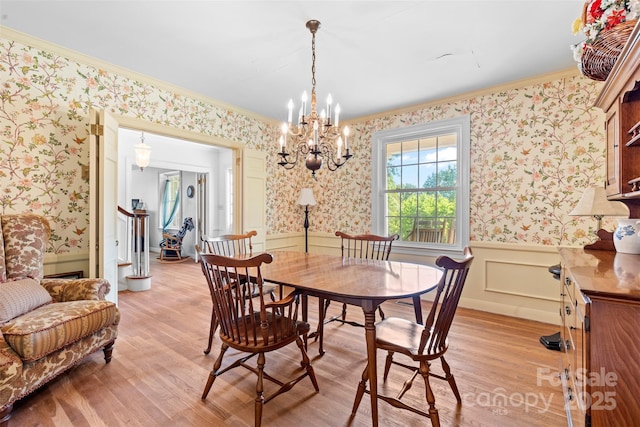 dining area with ornamental molding, light wood finished floors, wainscoting, and wallpapered walls