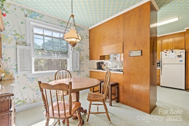 dining space with ornamental molding, light carpet, and wallpapered walls