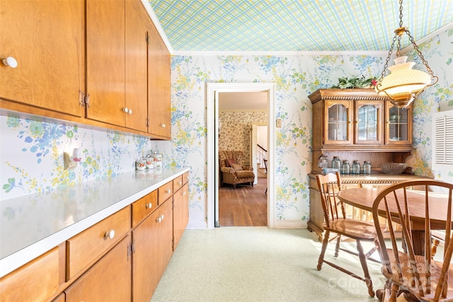 kitchen featuring pendant lighting, baseboards, wallpapered walls, light countertops, and brown cabinets