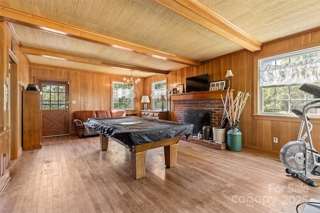 game room featuring a brick fireplace, beam ceiling, wooden walls, and hardwood / wood-style floors