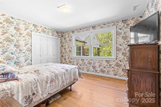bedroom featuring baseboards, light wood-style flooring, a closet, and wallpapered walls