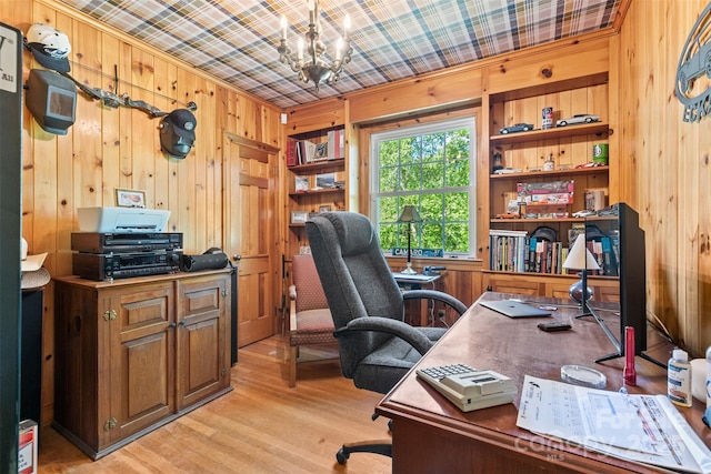 office area with wooden walls, an inviting chandelier, and light wood-style floors