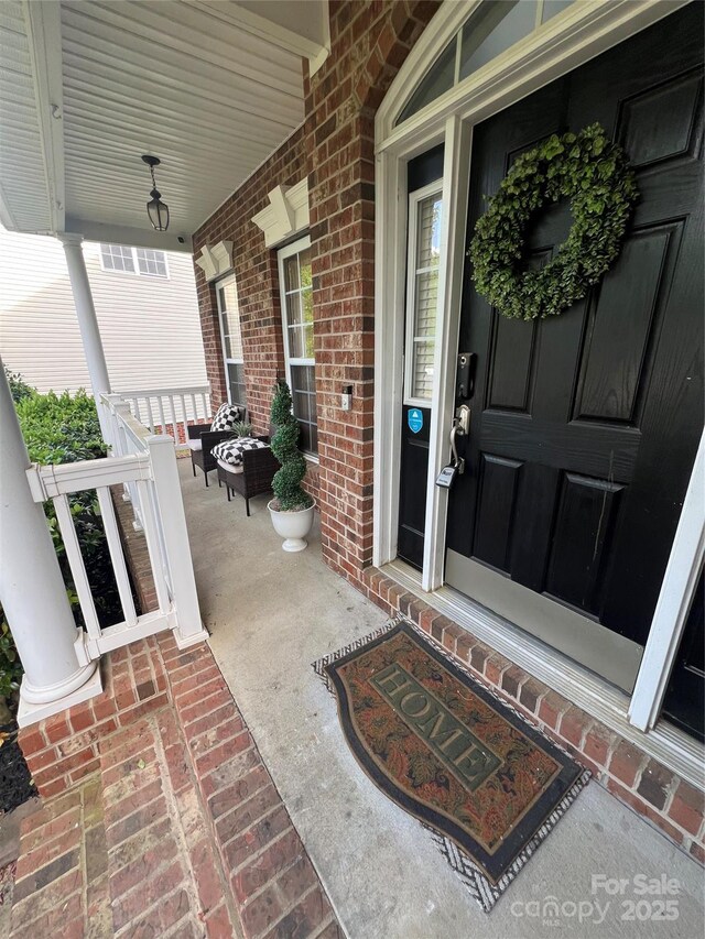 entrance to property featuring a porch and brick siding