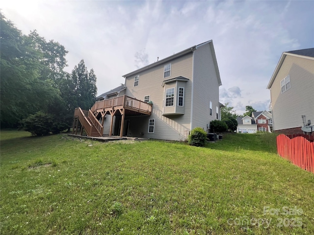 rear view of house featuring fence, a lawn, a deck, and stairway