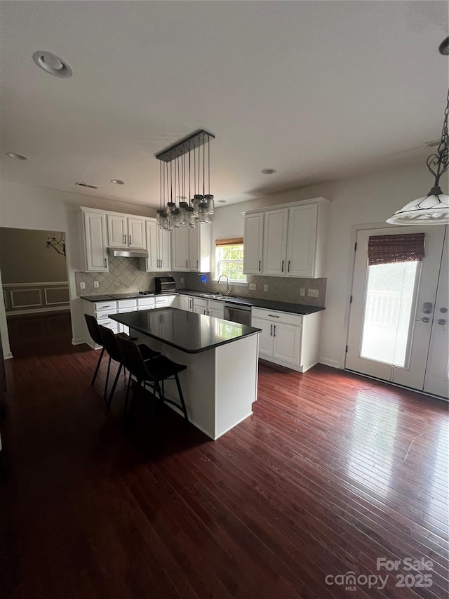kitchen with dark countertops, decorative backsplash, dark wood-style flooring, and white cabinets
