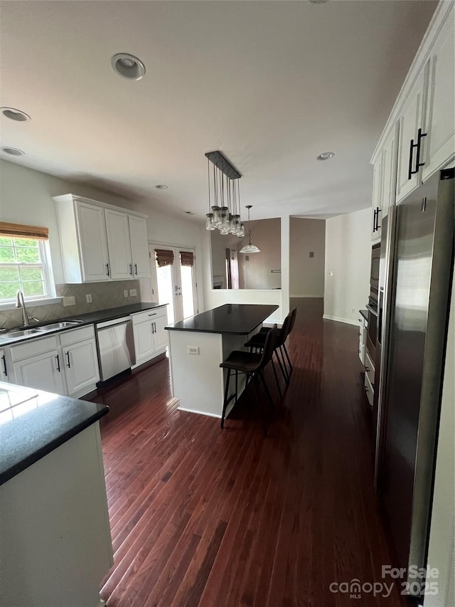 kitchen featuring a sink, appliances with stainless steel finishes, dark wood-style floors, and a wealth of natural light