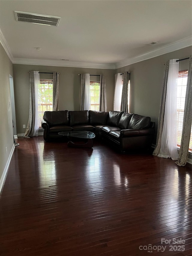 living area with a healthy amount of sunlight, crown molding, dark wood-style floors, and visible vents