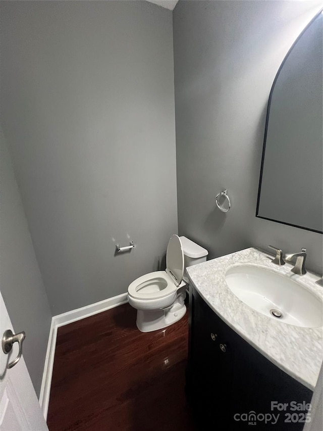 half bath featuring vanity, toilet, and wood finished floors