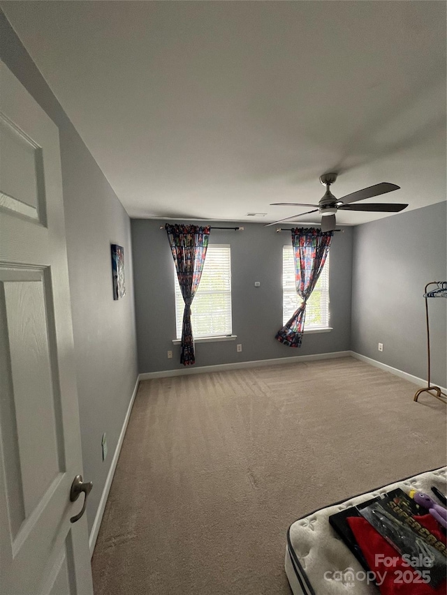 carpeted empty room featuring baseboards and a ceiling fan
