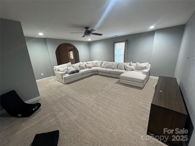 carpeted living room with arched walkways, ceiling fan, baseboards, and recessed lighting