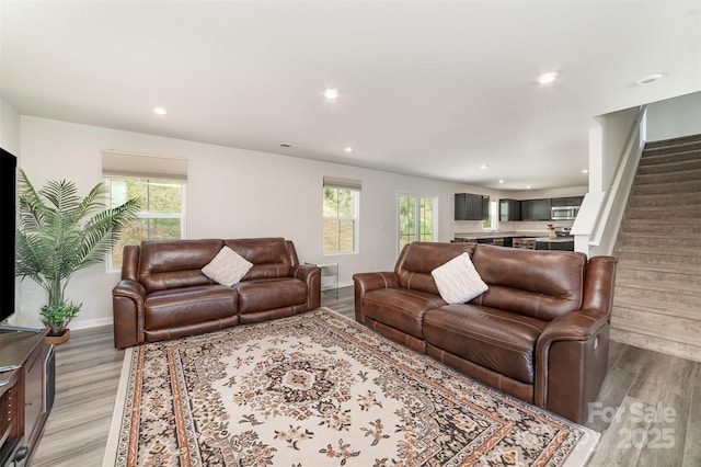 living area featuring recessed lighting, light wood finished floors, plenty of natural light, and stairs