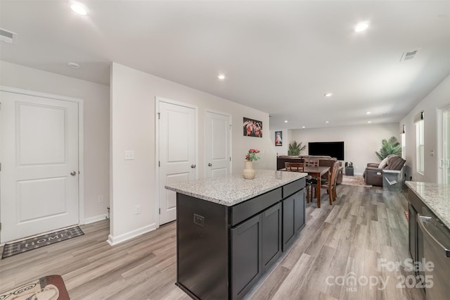 kitchen featuring light wood-type flooring, recessed lighting, light stone counters, and a center island
