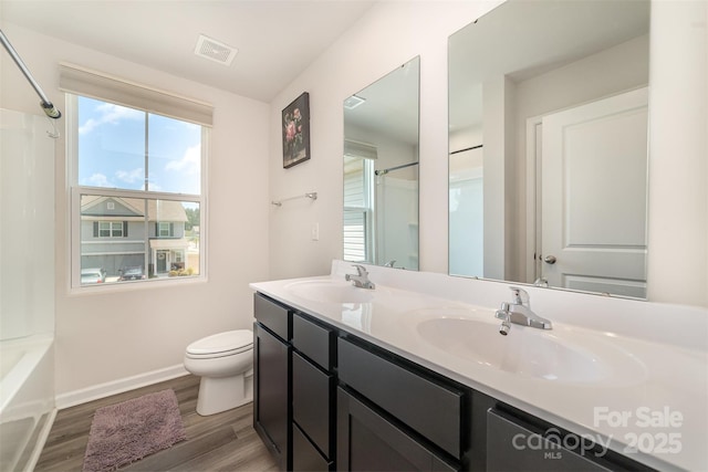 bathroom featuring toilet, visible vents, a sink, and wood finished floors