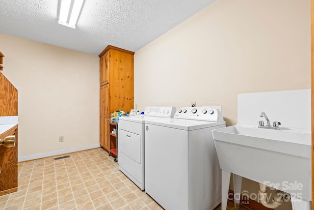 laundry area with cabinet space, washer and dryer, a textured ceiling, baseboards, and visible vents