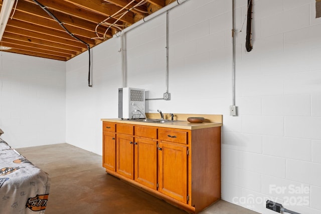 basement with concrete block wall and a sink
