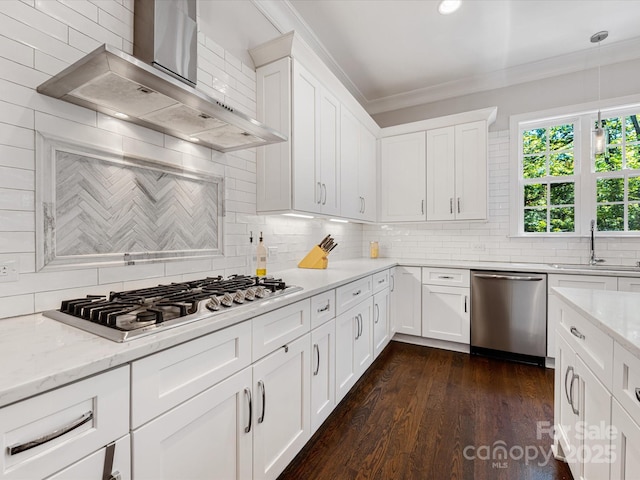 kitchen featuring ornamental molding, wall chimney range hood, tasteful backsplash, a sink, and stainless steel appliances
