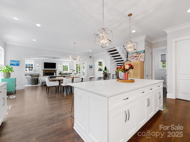 kitchen with crown molding, white cabinets, a kitchen island, and a chandelier