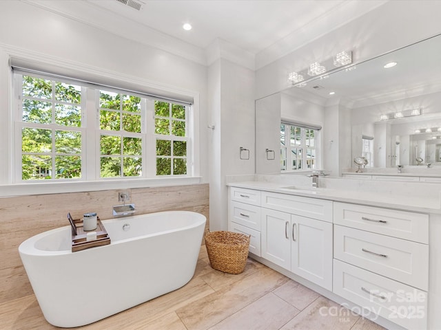 bathroom featuring crown molding, a wealth of natural light, and vanity