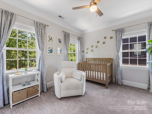 bedroom with a ceiling fan, visible vents, crown molding, a nursery area, and baseboards