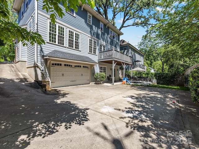 view of front of house featuring an attached garage, a balcony, fence, and driveway